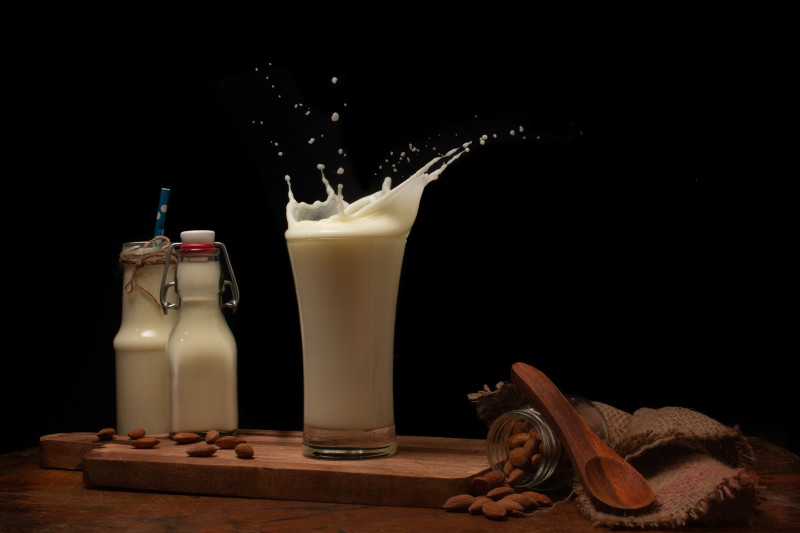 Bottles glass wooden spoon and jute with milk on the table