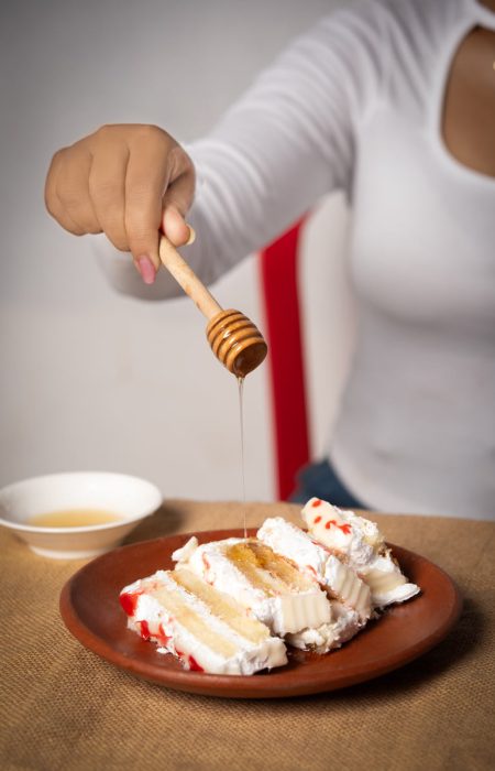 a girl dripping honey on a cake