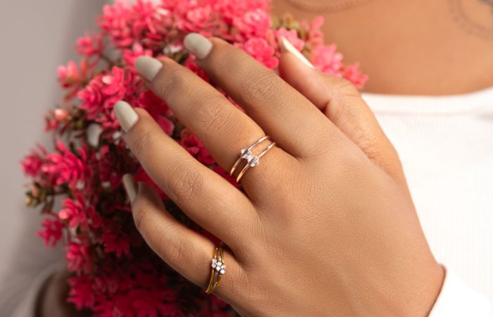 a girl is holding red flower and showcasing her ring.