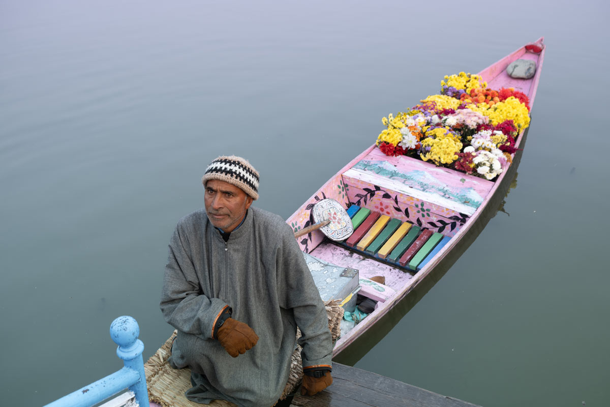 A man selling flowers in lake with boats