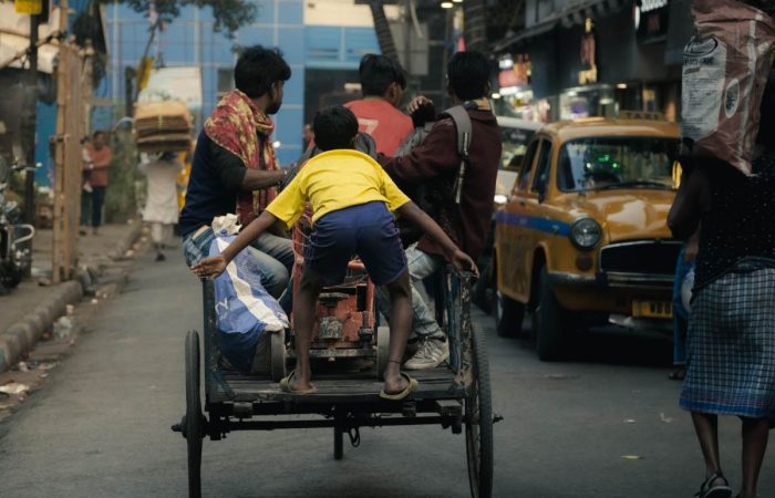 a kid jumps on to a street rickshaw.