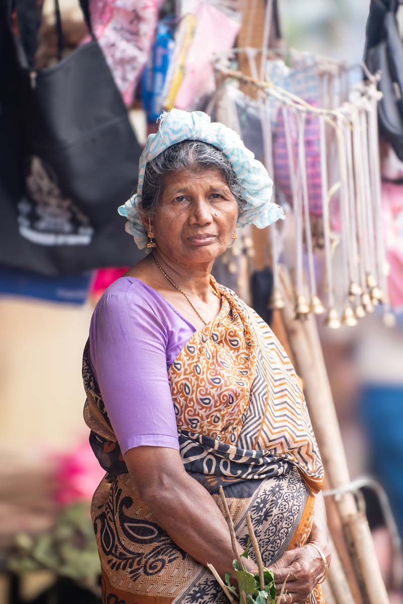 A aged mother standing Infront of her shop.