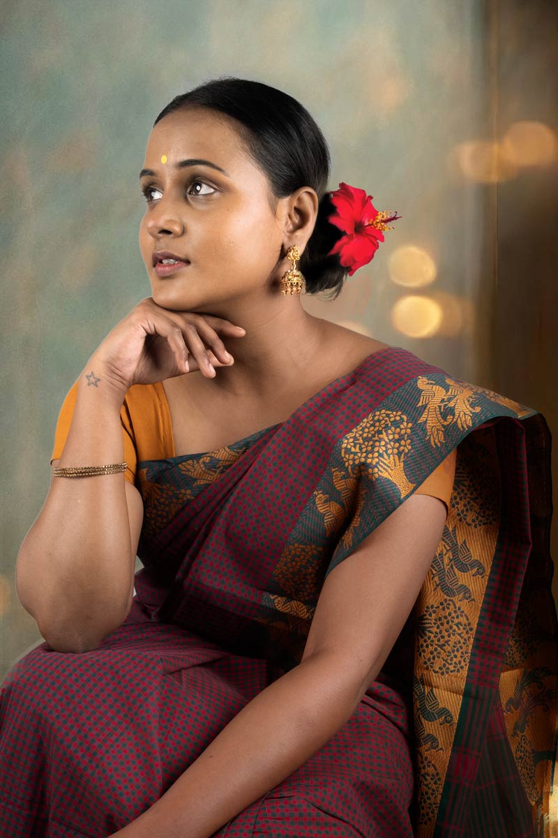 A woman in traditional outfit with hibiscus flower