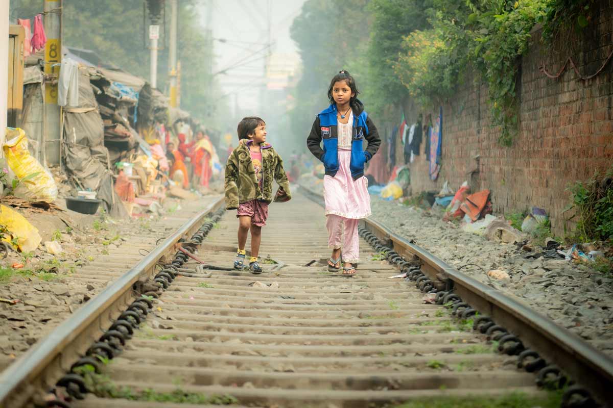 two little girls are walking over railway track