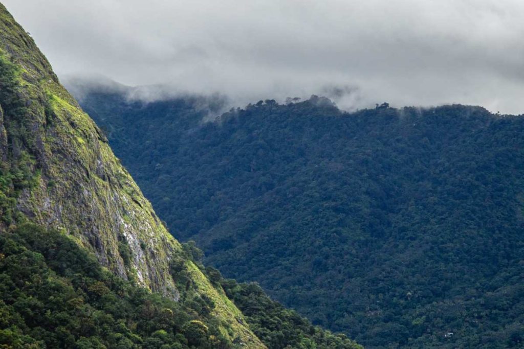 The clouds are touching the hills as they are passing by.