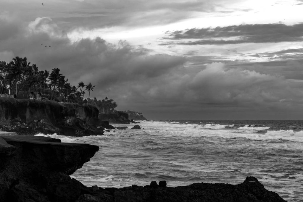 Sea waves meet the cliff with a vast sky.