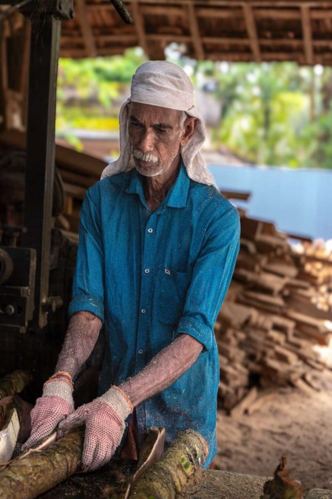 An old man wearing a handglouse along with a white towel to his head..