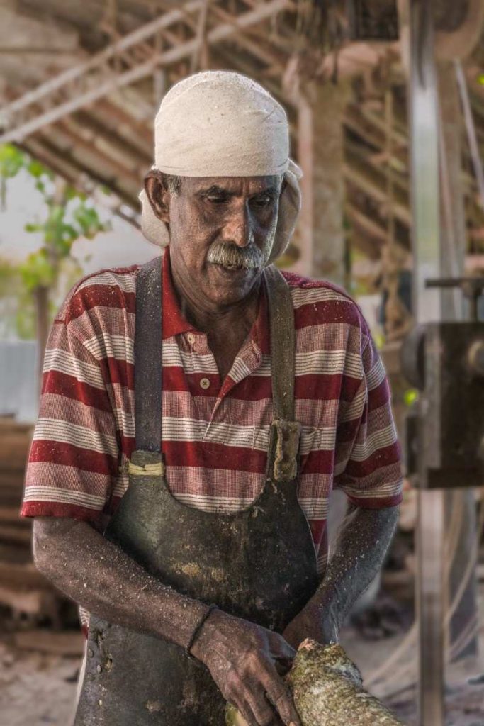 An old man wearing an apron and white towel.