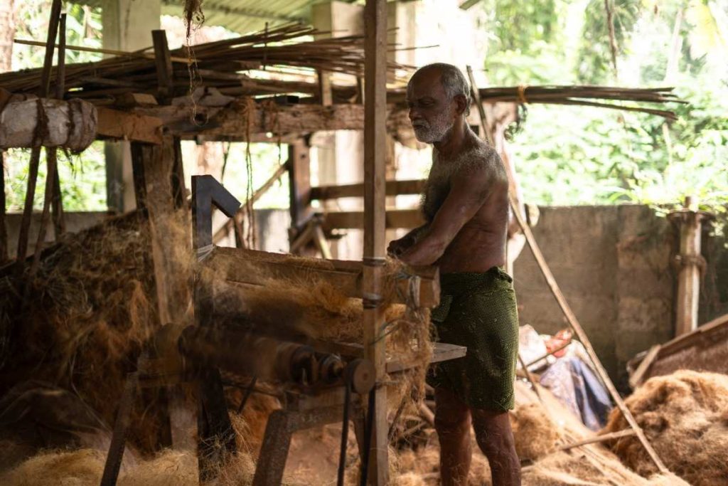 Weaving Wisdom An elderly man operating a coir-making machine.