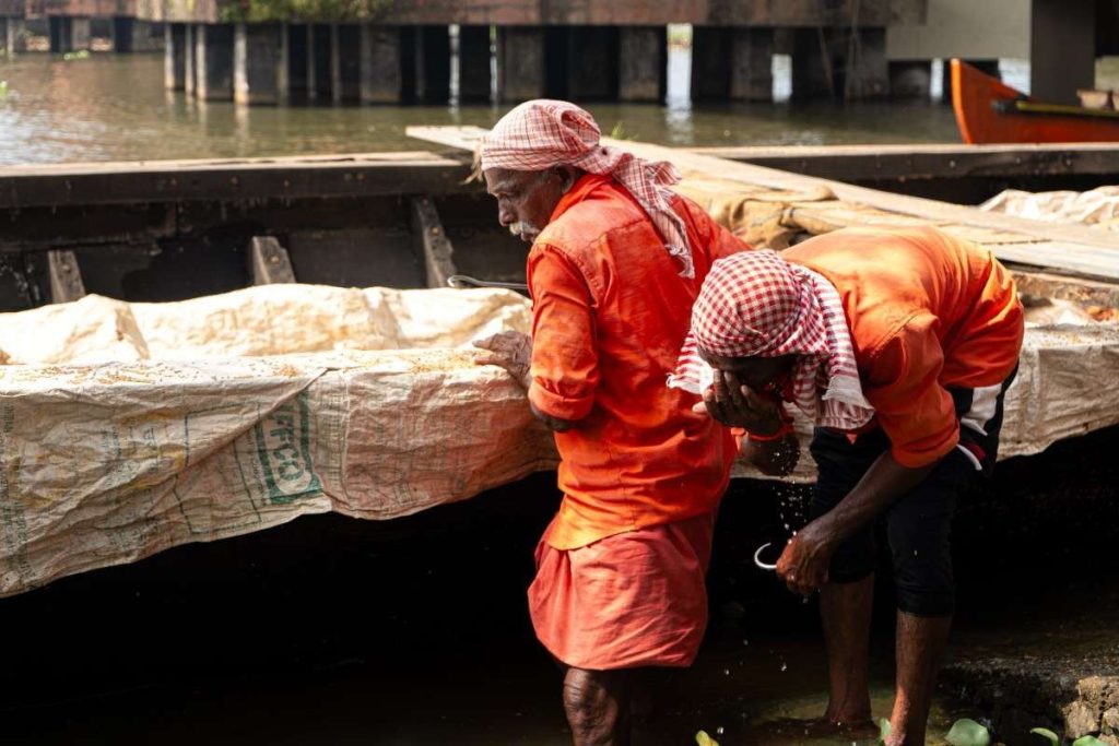 Refreshing Two workers wash their faces near a boat.