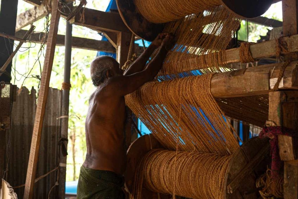 Rope Fitting Man working on a coir rope weaving machine.