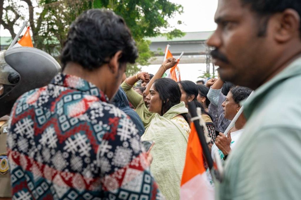 Women strength leads a protest, raising her voice amid a crowd with flags.