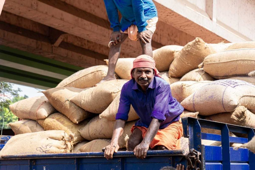 Cycle Complete A smiling worker sits on a truck loaded with sacks.