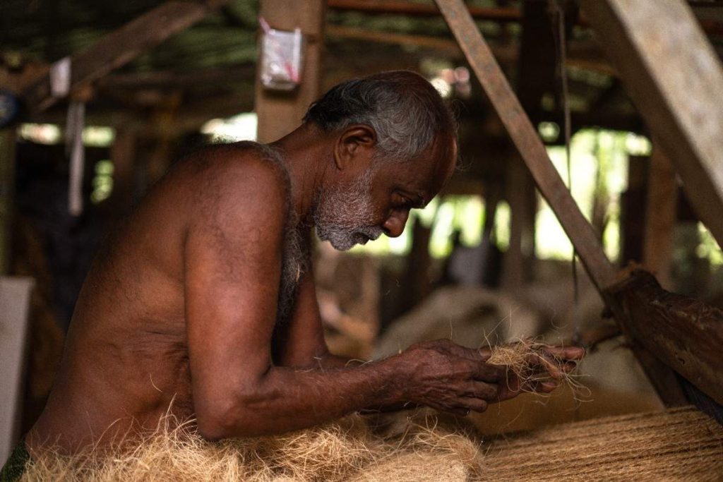 PrecisionElderly man sorting coir fibers in a workshop.