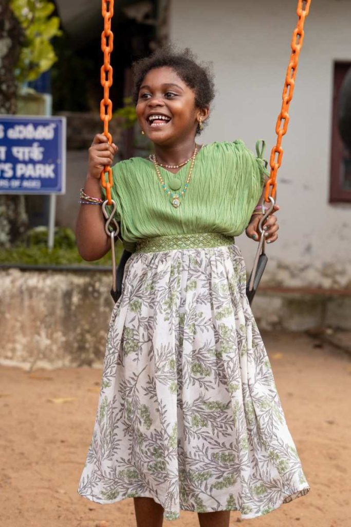 Bliss A smiling girl in a green dress swings.