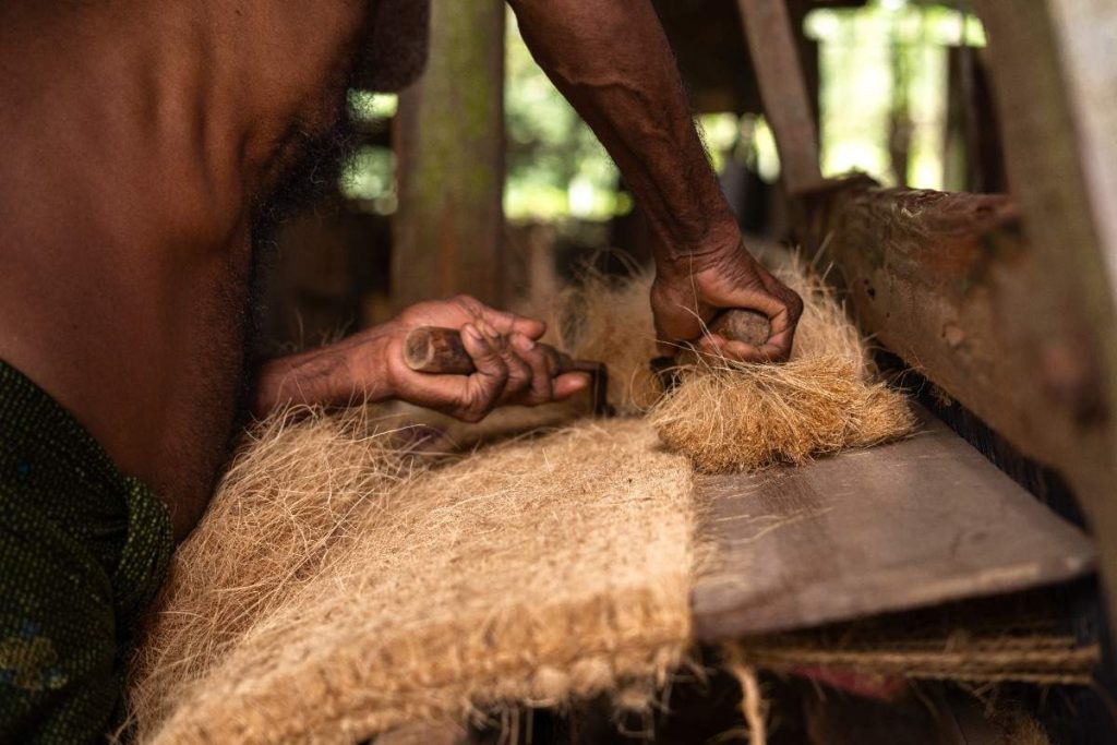 Clean Process Worker trims coconut fiber with tools.