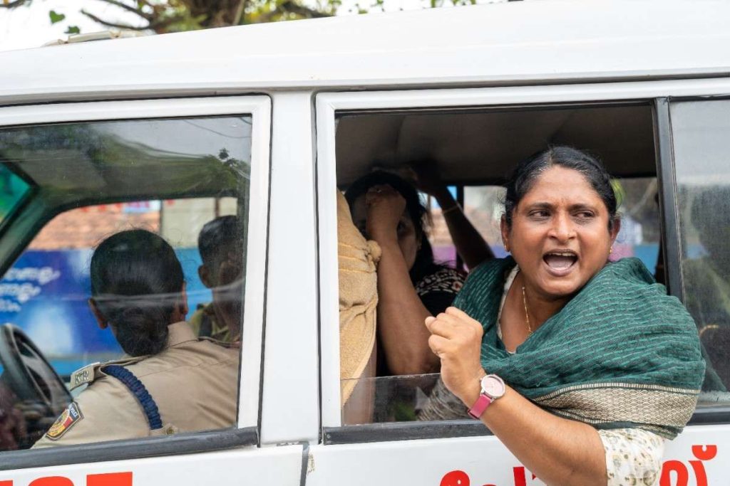 Defiant protest a woman shouts from inside a police vehicle while being detained.