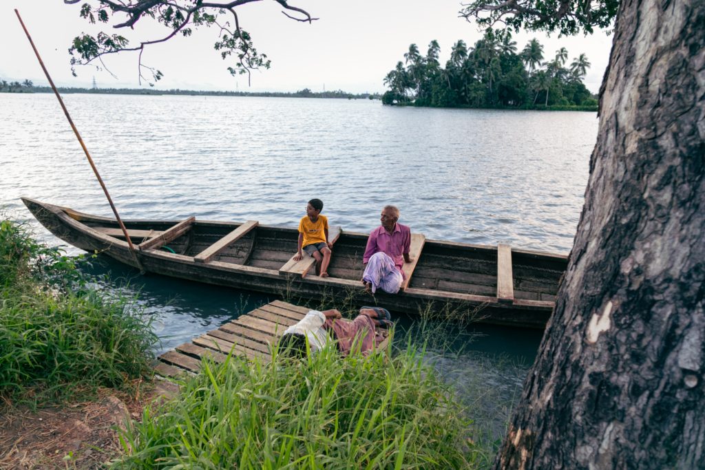 An innocent boy and an aged man sit on a boat.