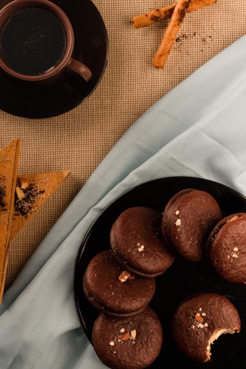 Cozy treats of choco pies on a plate with black coffee.