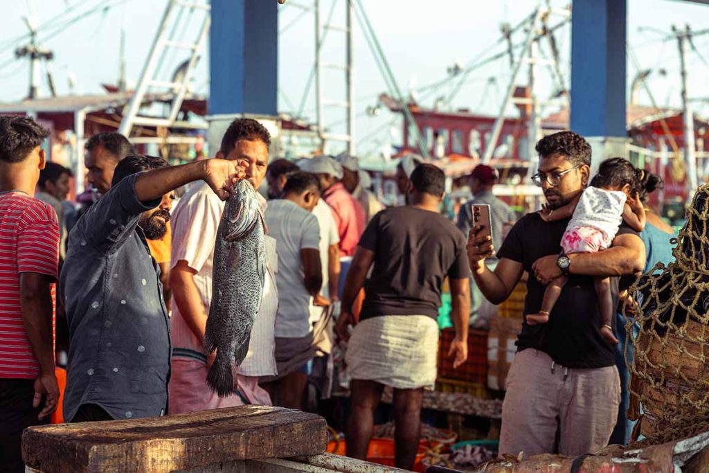 A man showing off fresh fish to the buyer.