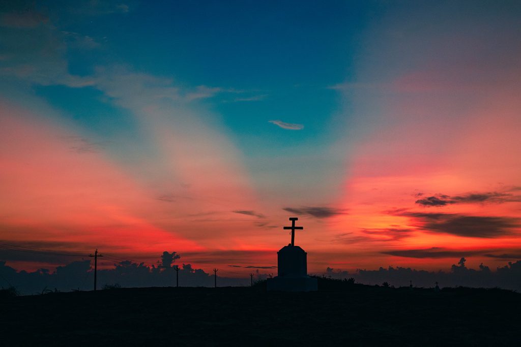 Heaven’s Glow Cross on hill at sunset.