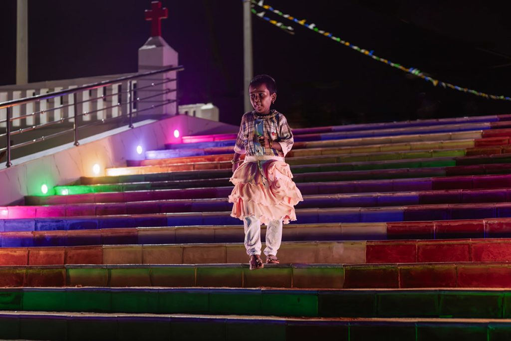 Illuminated Descent Child on colorful temple stairs.