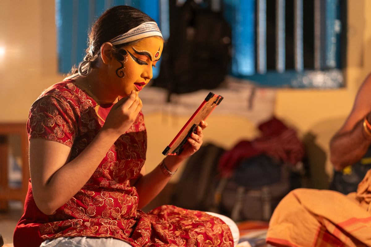 Performer applying Makeup Ritual in mirror.