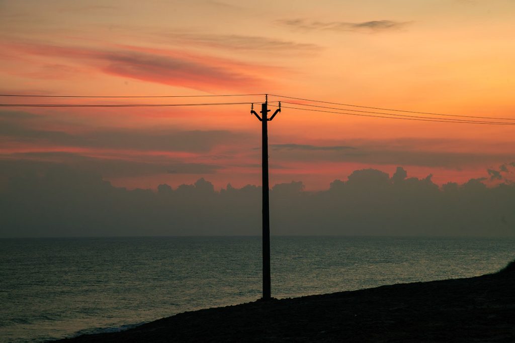 Man and Nature  An electric post atop a hill. 