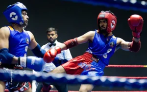 Boxer in red headgear lunging with a punch in the ring, sports photograph by Joyal Joseph, Creative Hut Academy