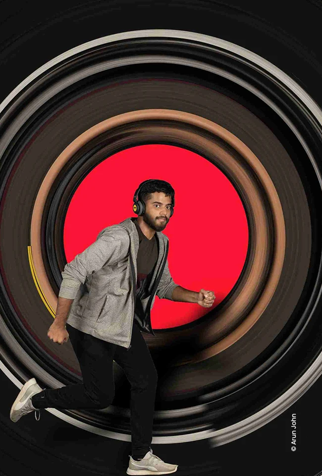 Man in a jacket running through a camera lens tunnel, advertising photograph by Arun John, Creative Hut Academy