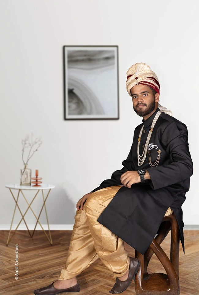 Man in a turban and sherwani seated in a white room, advertising photograph by Sahil Sidharthan, Creative Hut Academy