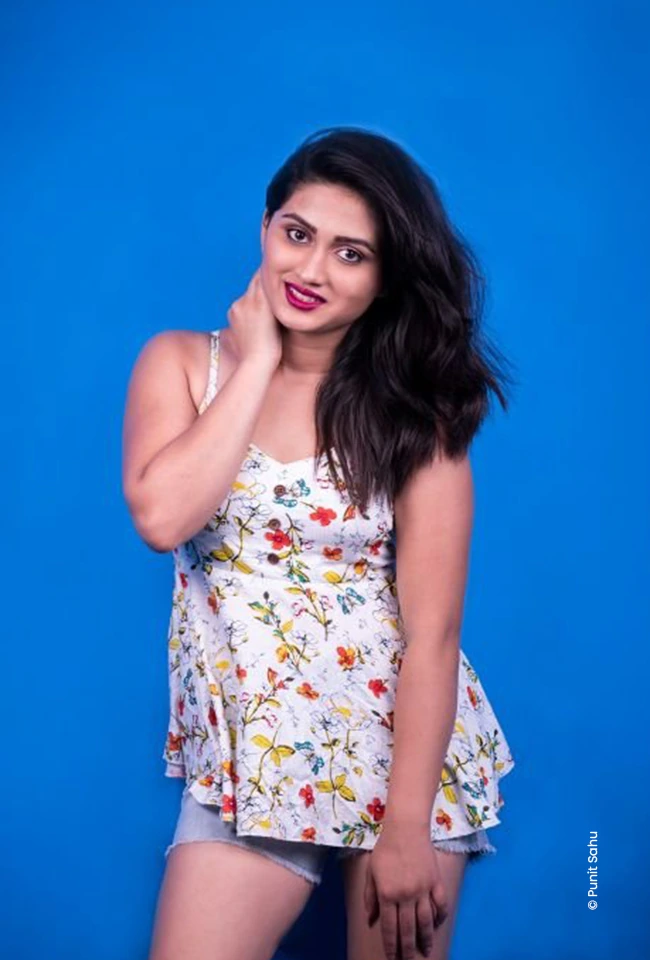 Woman in a floral top posing against a blue wall, advertising photograph by Punit Sahu, Creative Hut Academy