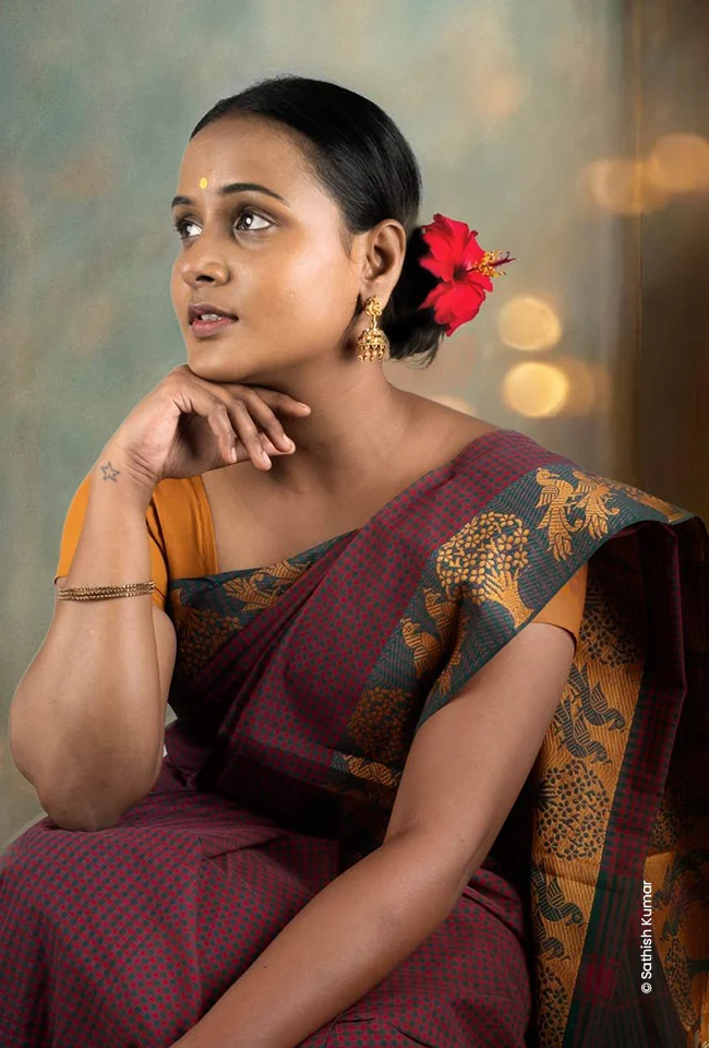 Woman in a maroon saree gazing sideways, advertising photograph by Sathish Kumar, Creative Hut Academy