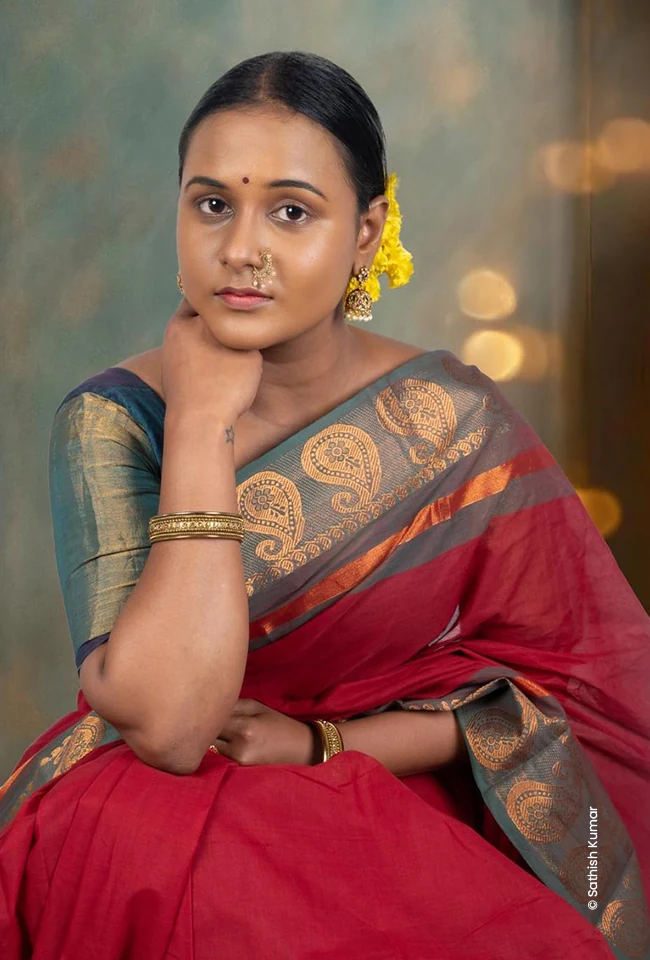 Woman in a red saree resting her chin on her hand, fashion photography courses at Creative Hut Academy