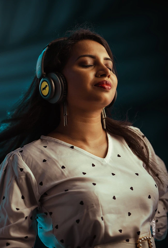 Woman in headphones listening to music with eyes closed, advertising photograph by Athul A, Creative Hut Academy